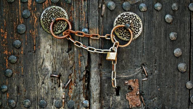 A weathered door with a padlock and chain.
