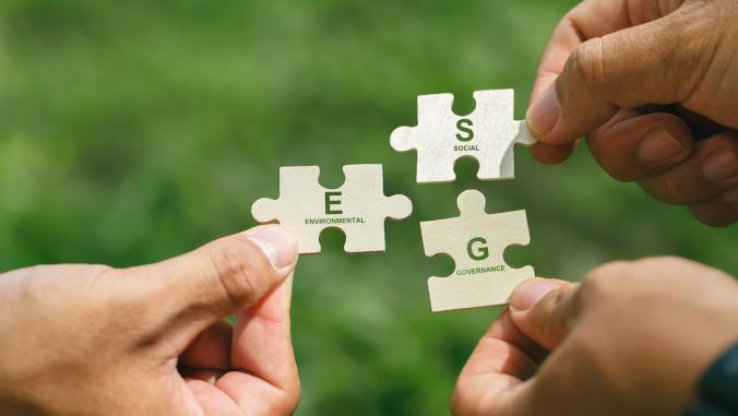 Hands of people holding E, S, G pieces of a jigsaw puzzle to form the word ESG