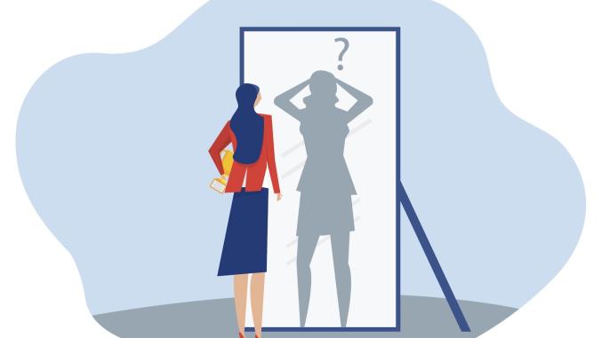 Businesswoman looking at herself in mirror and seeing an anxious shadow
