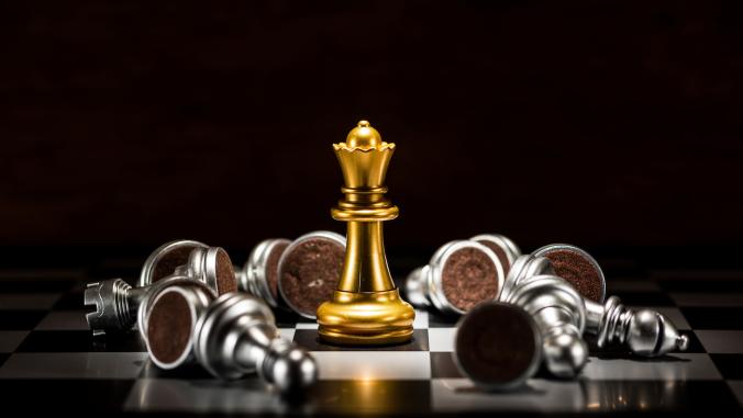 Chess pieces with one gold queen still standing
