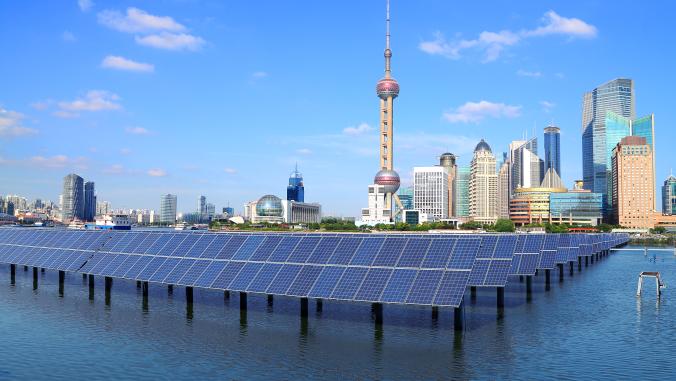 A picture of Beijing's skyline with a field of solar panels propped up in the water before it 