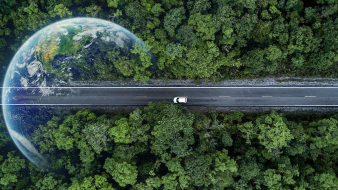 Car on forest road with Planet Earth imposed on forest